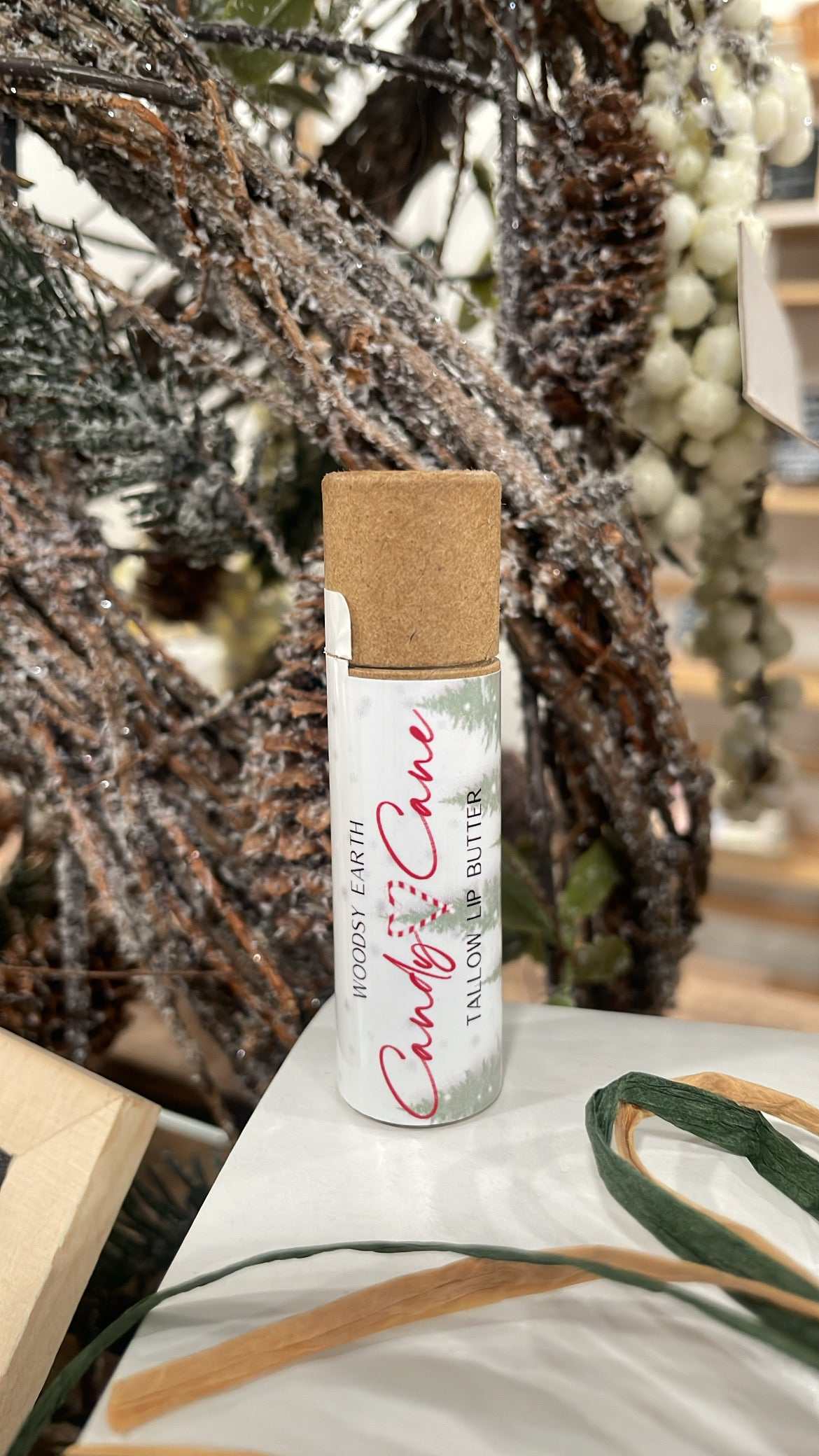Candy Cane Tallow Lip Butter with peppermint and vanilla essential oils, displayed in a festive holiday setting
