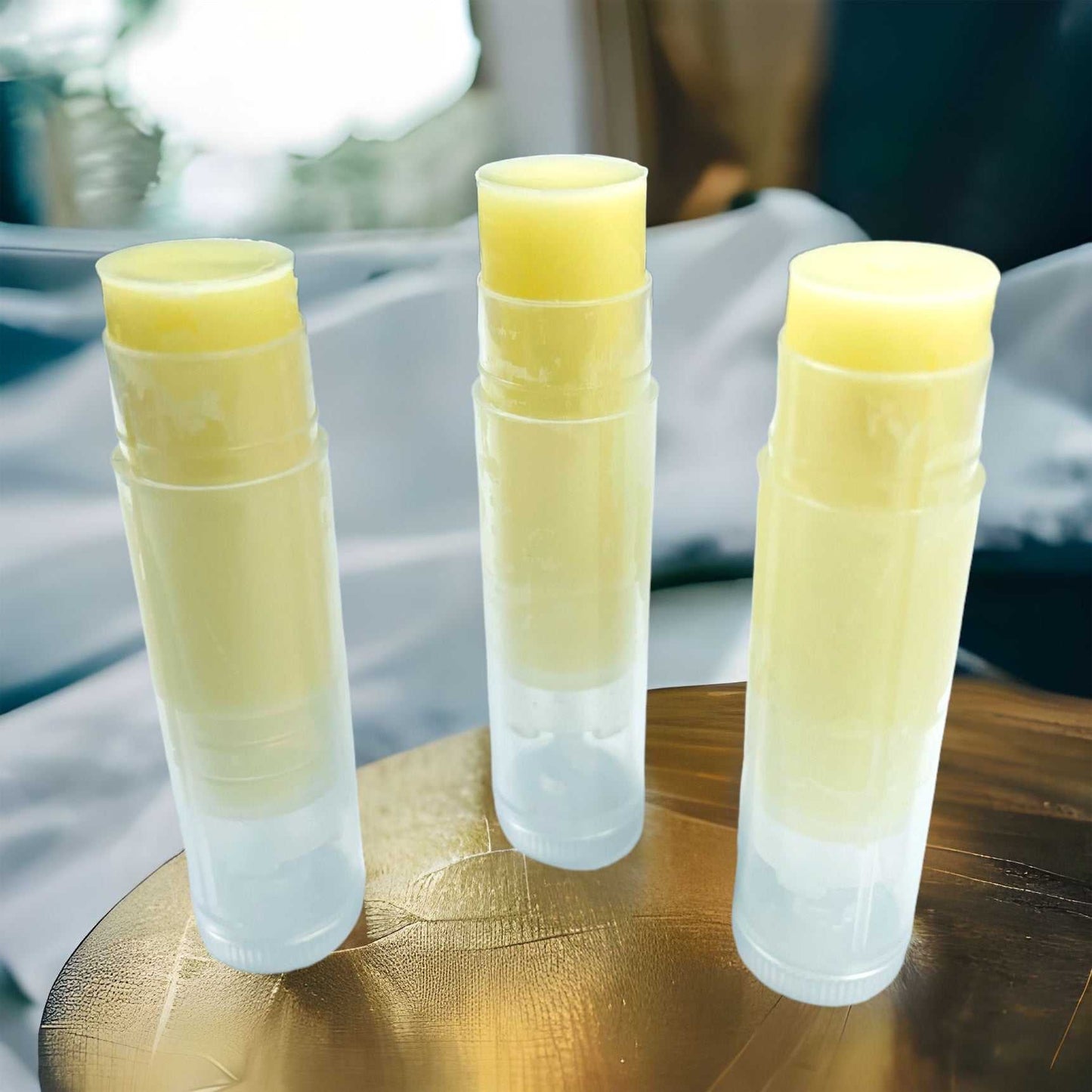 Unlabeled Woodsy Earth Mochaccino Tallow Lip Balm tubes on wooden surface, showing creamy natural texture.