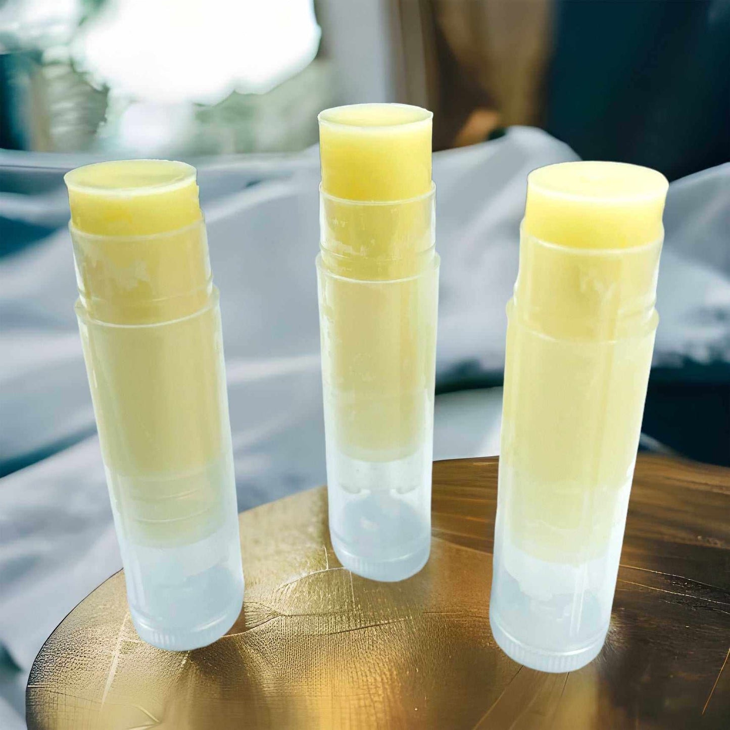 Unlabeled Woodsy Earth Vanilla Mint Tallow Lip Balm tubes on wooden surface, showing creamy natural balm.