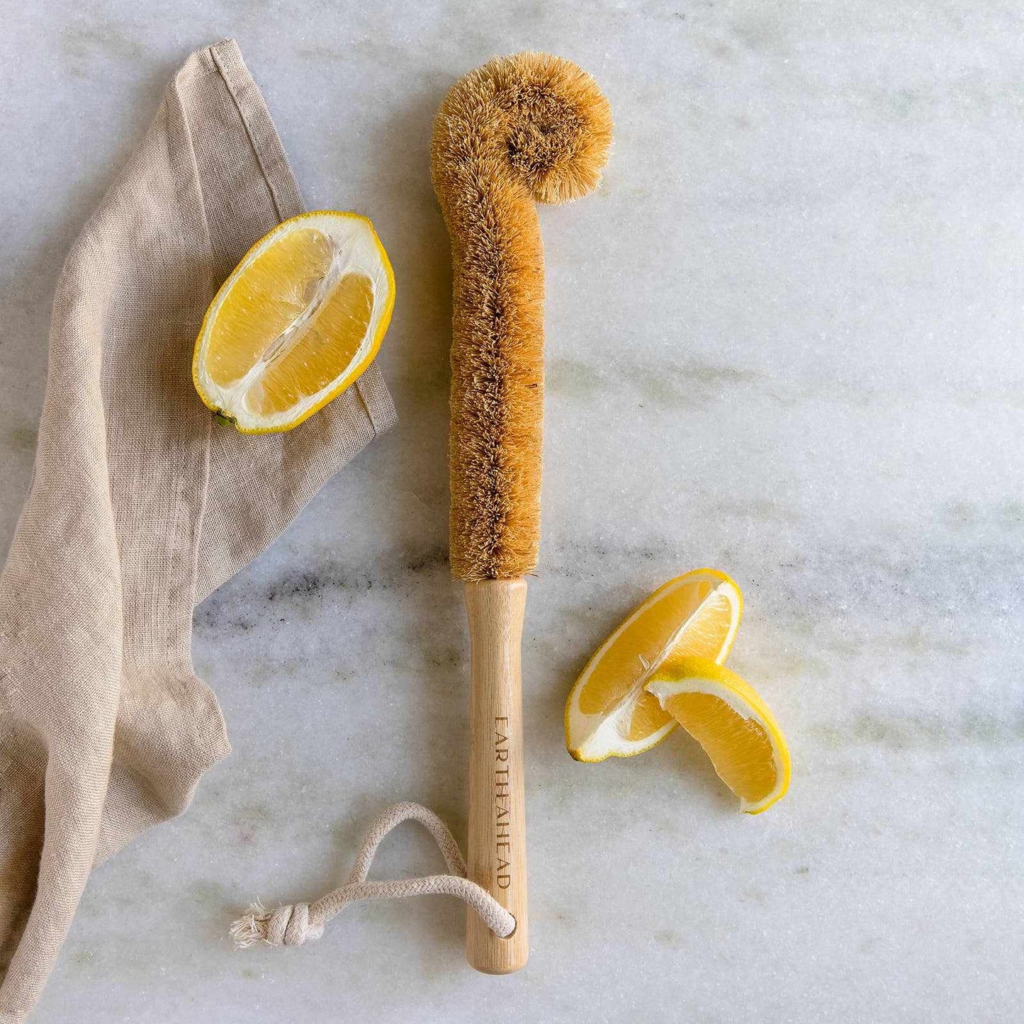 Earth Ahead eco-friendly bamboo coconut bottle brush on marble surface with sliced lemon.