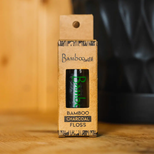 Bamboo Switch Charcoal Bamboo Floss in eco-friendly packaging on wooden surface.