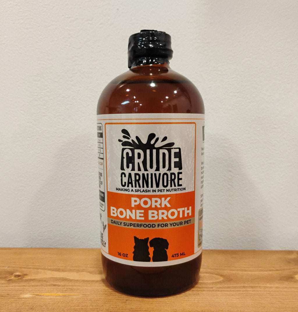 Crude Carnivore Pork Bone Broth bottle on a wooden surface.