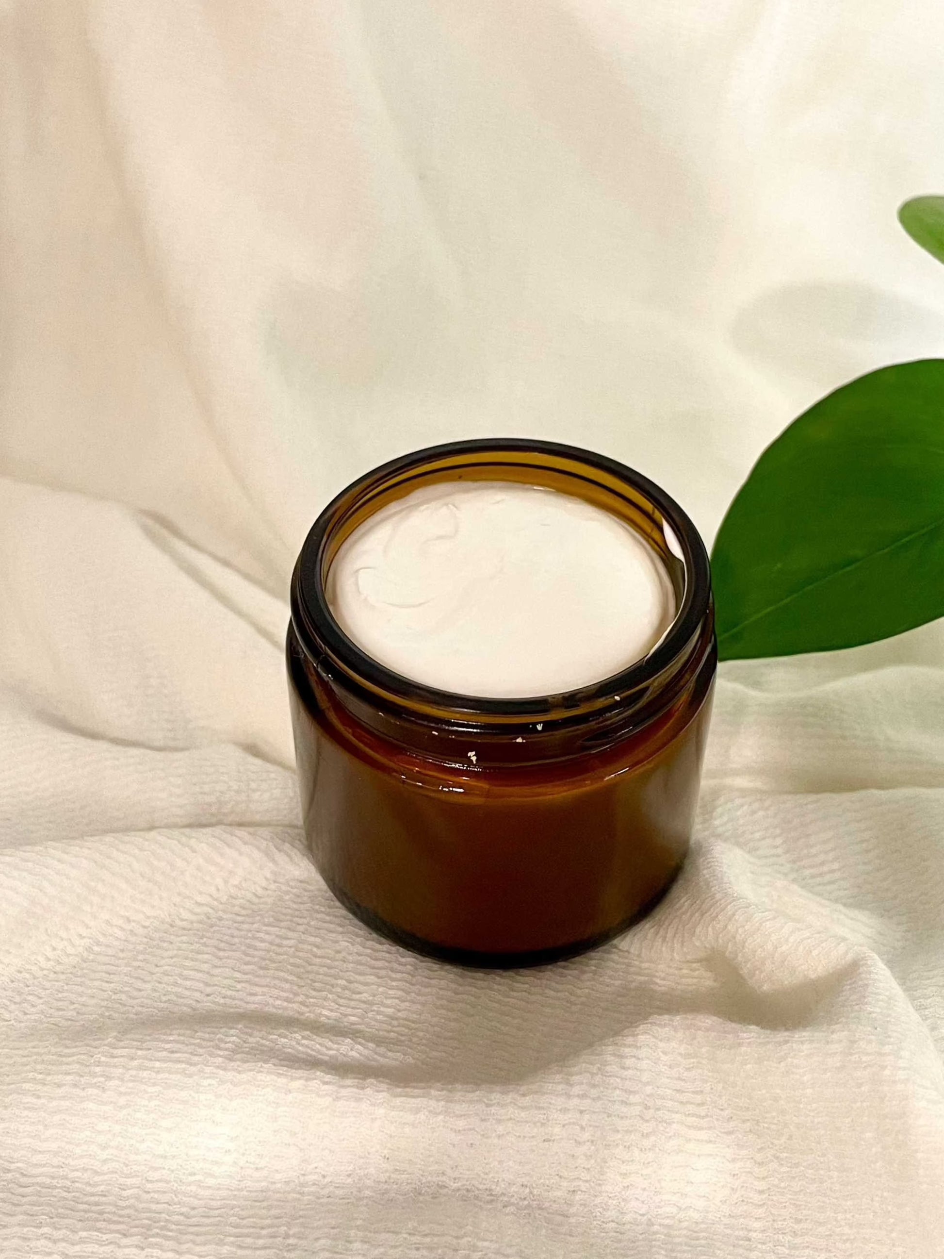 Sweet Beginnings Baby Cream in 2 oz amber jar on white cloth background.