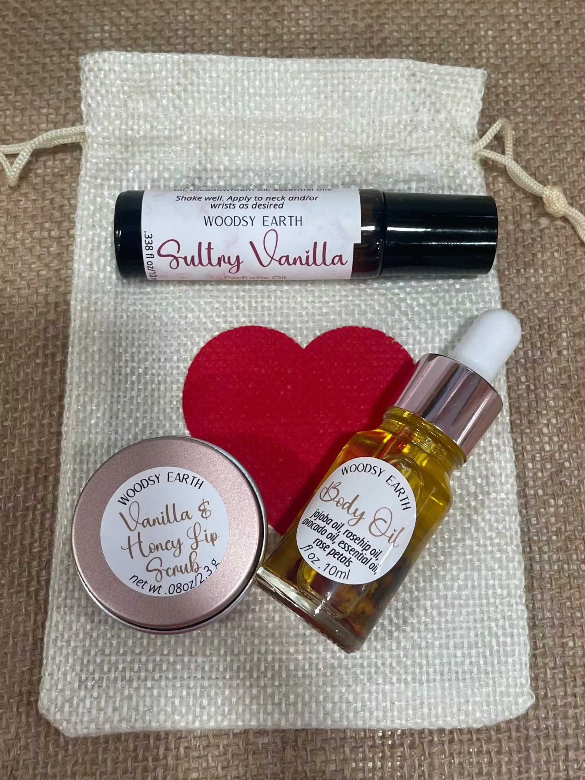 Valentine's gift set with body oil, lip scrub, and perfume roll-on in a decorative bag.