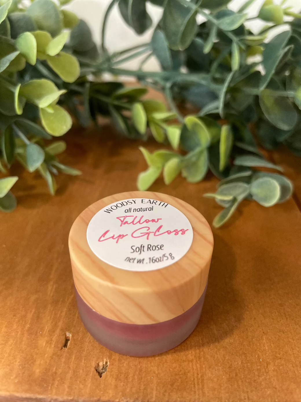 Tinted Tallow Lip Gloss in a wooden cap container, providing natural moisture and color.