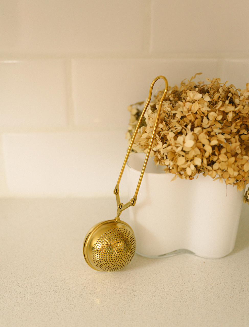 Bamboo Switch gold stainless steel tea strainer on a countertop, eco-friendly infuser for loose leaf tea.