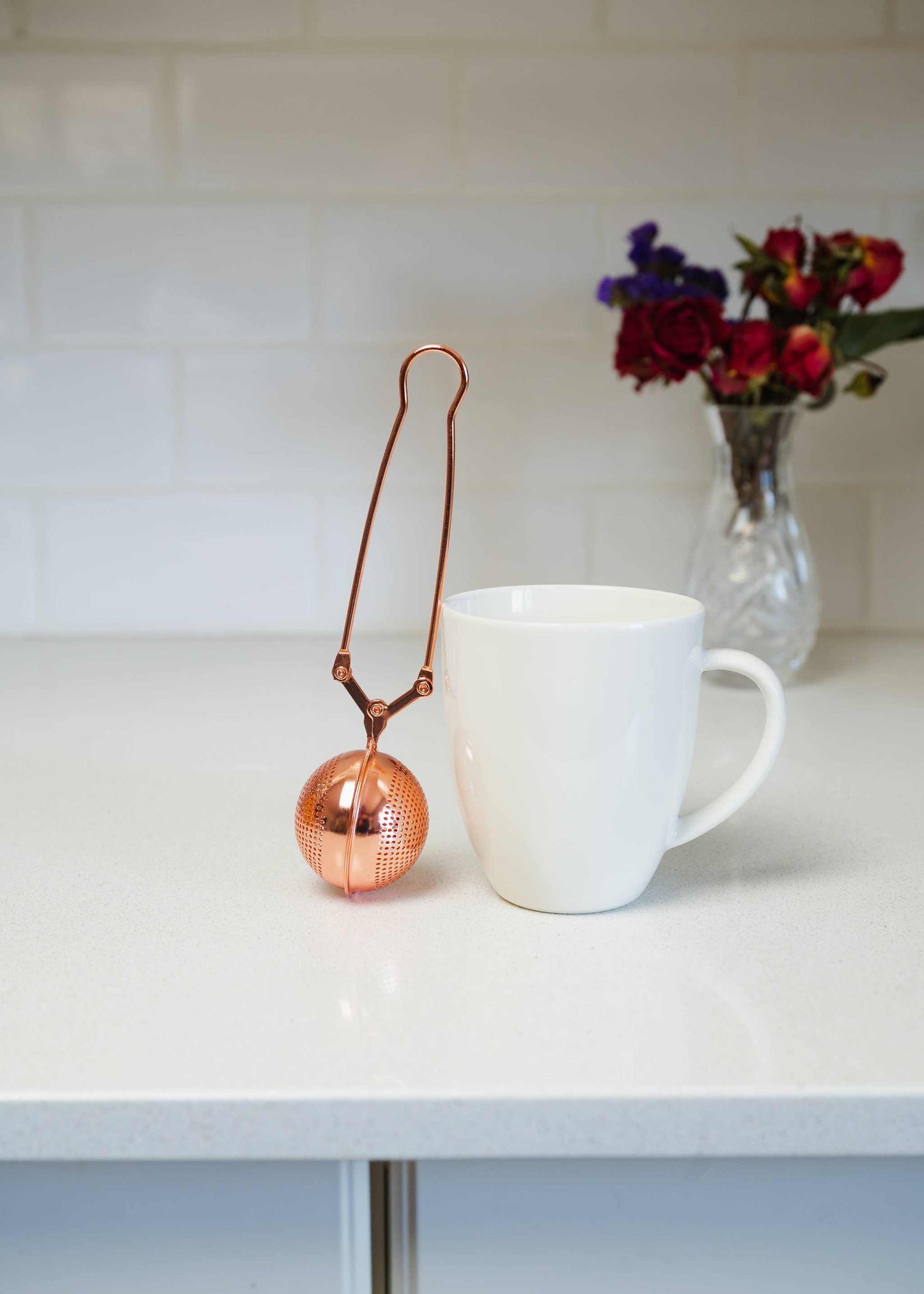 Bamboo Switch stainless steel tea strainer resting beside a white mug, reusable infuser for loose leaf tea.