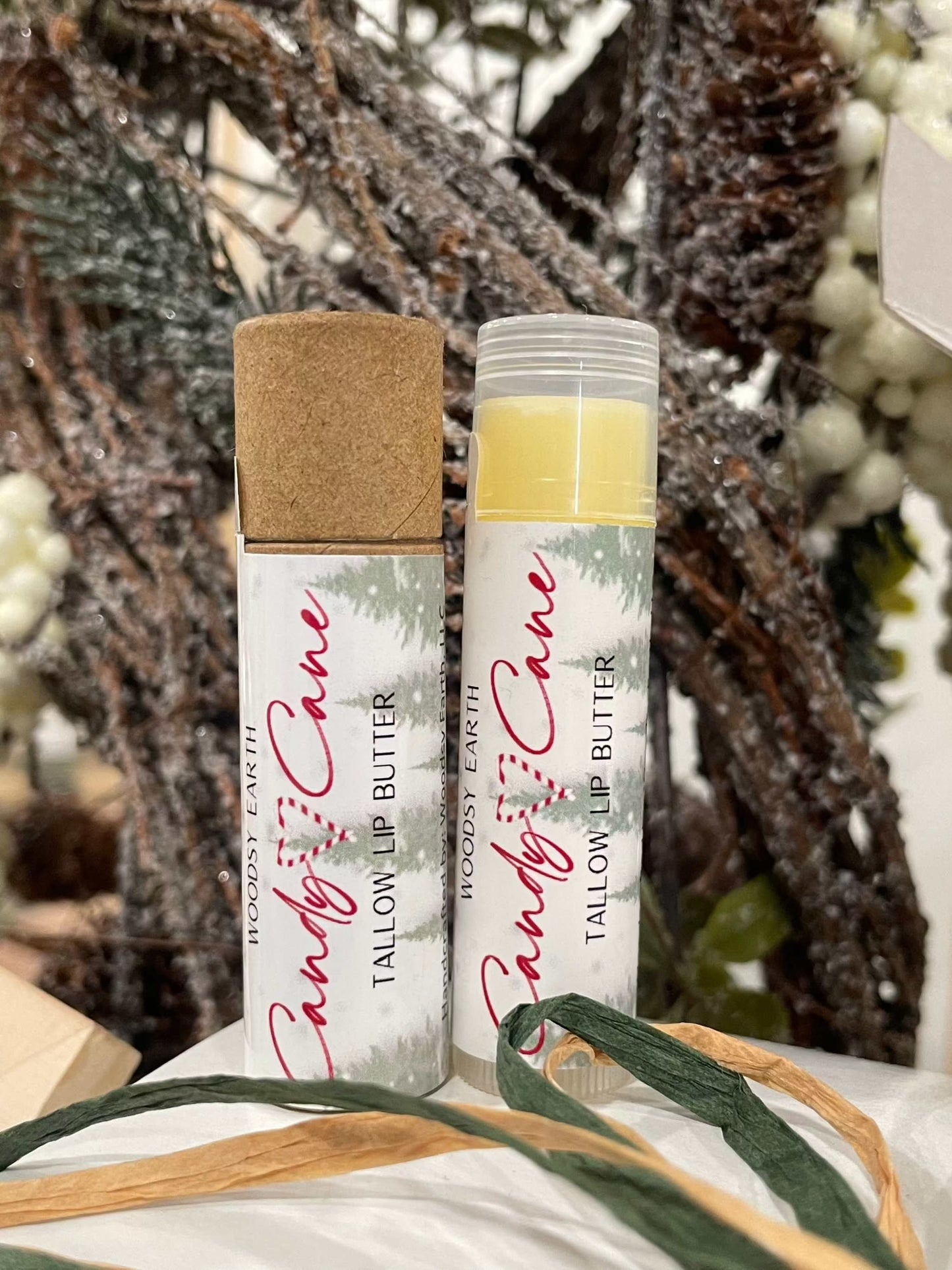 Candy Cane Tallow Lip Butter with peppermint, spearmint, and vanilla essential oils. Two tubes shown, one with cap on and one open, nourishing natural lip care
