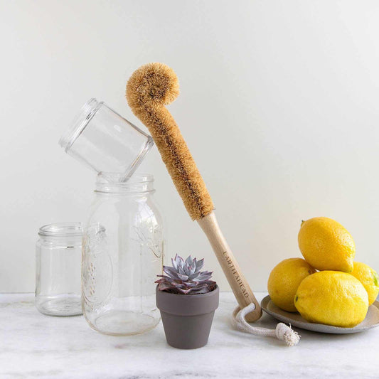 Earth Ahead bamboo and coconut bottle brush with glass jars and lemons.