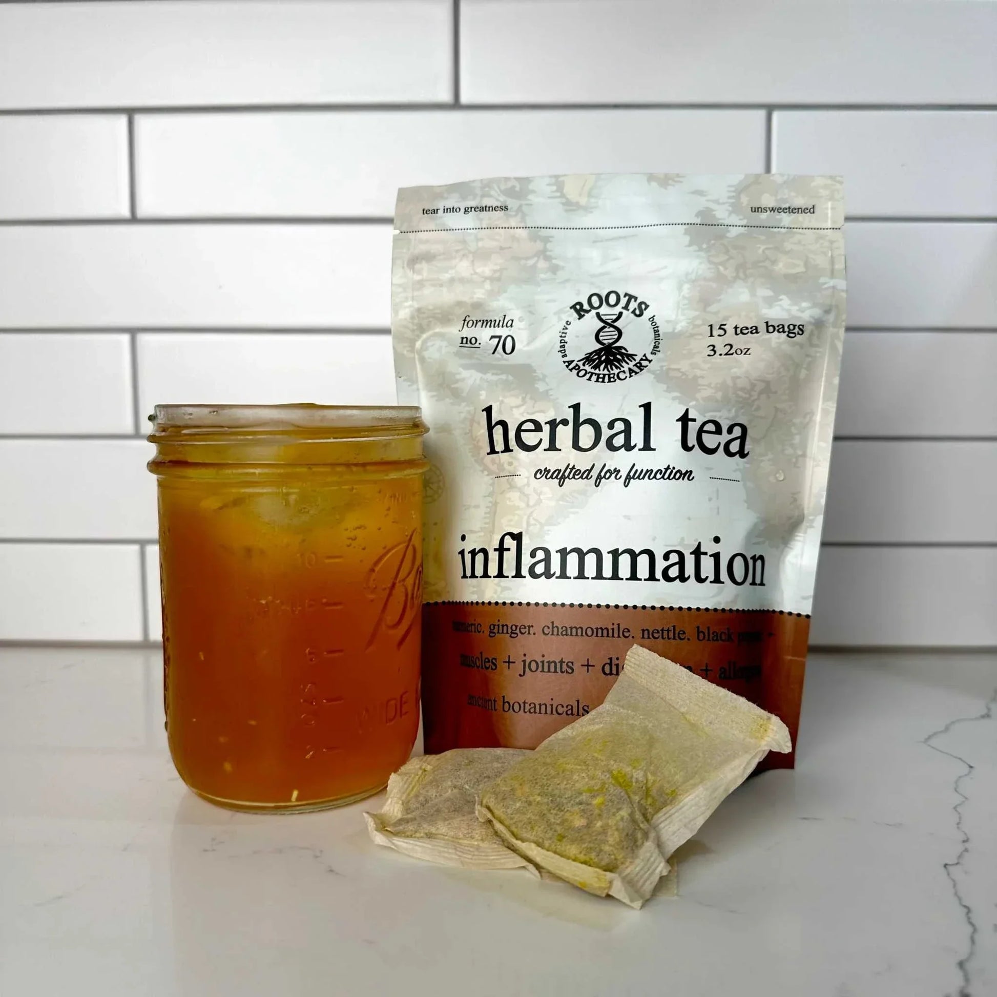 Roots Apothecary Inflammation Herbal Tea with brewed tea in mason jar and tea bags on counter
