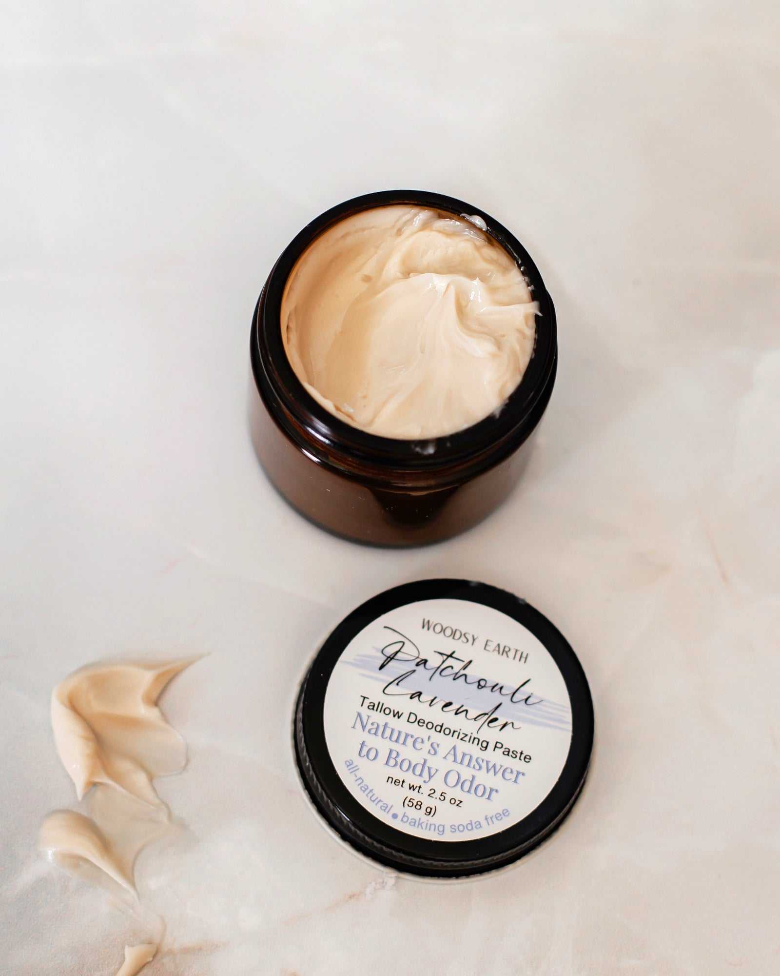 Woodsy Earth natural tallow deodorant paste in a 2 oz amber jar with patchouli scent, aluminum-free and baking soda free formula.