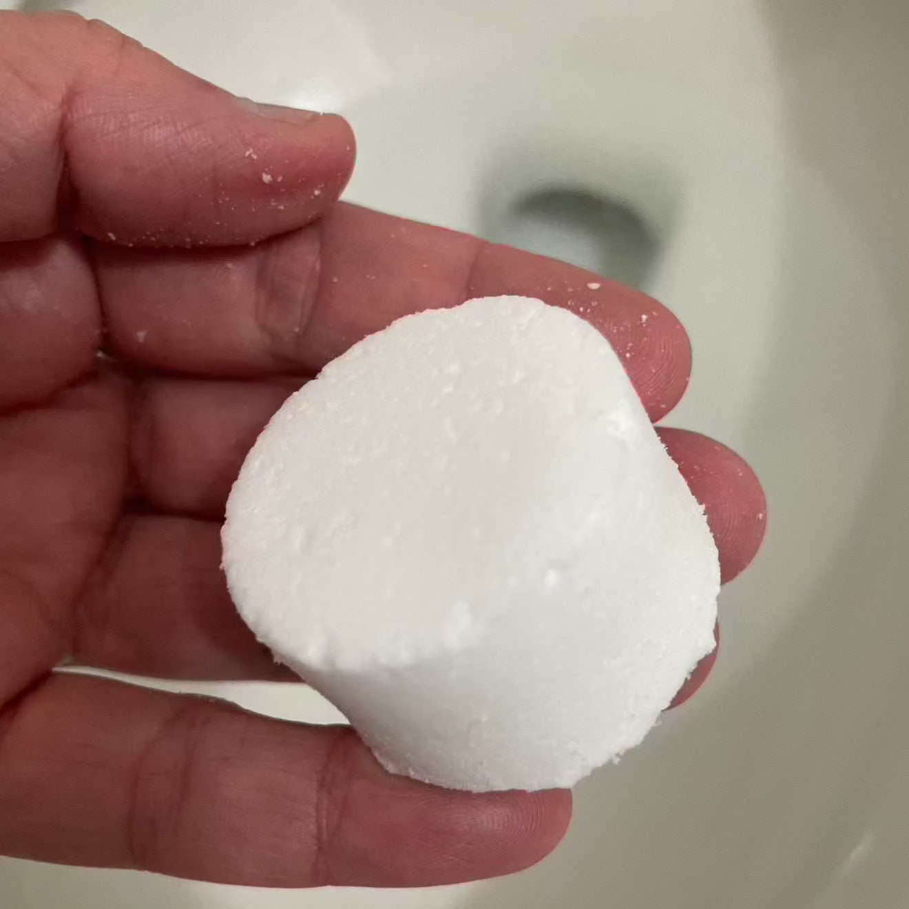Hand holding a natural toilet fizzy for eco-friendly cleaning and deodorizing.
