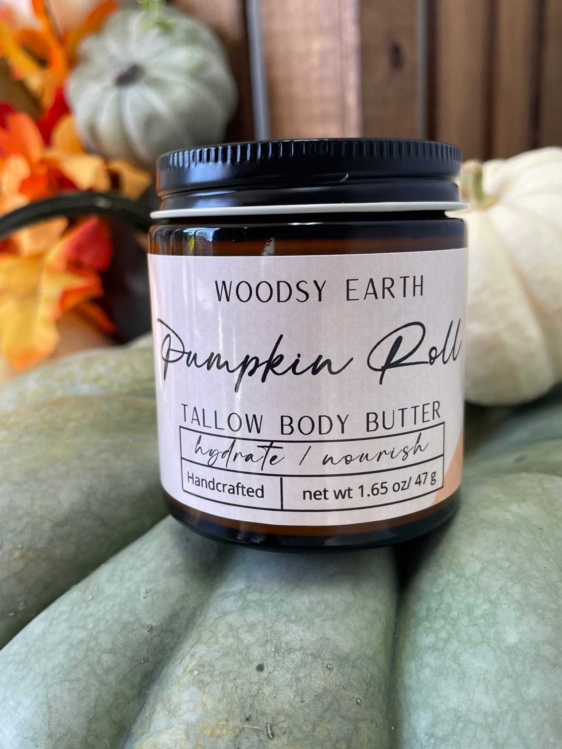 Woodsy Earth Pumpkin Roll Tallow Body Butter in amber jar with pumpkins and fall leaves, hydrating and nourishing handcrafted skincare