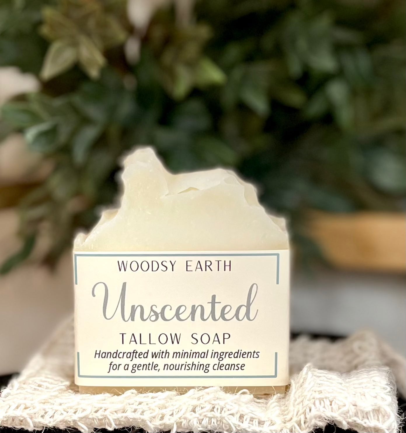 Woodsy Earth Unscented Tallow Soap bar with creamy ivory color, displayed on textured cloth with greenery background