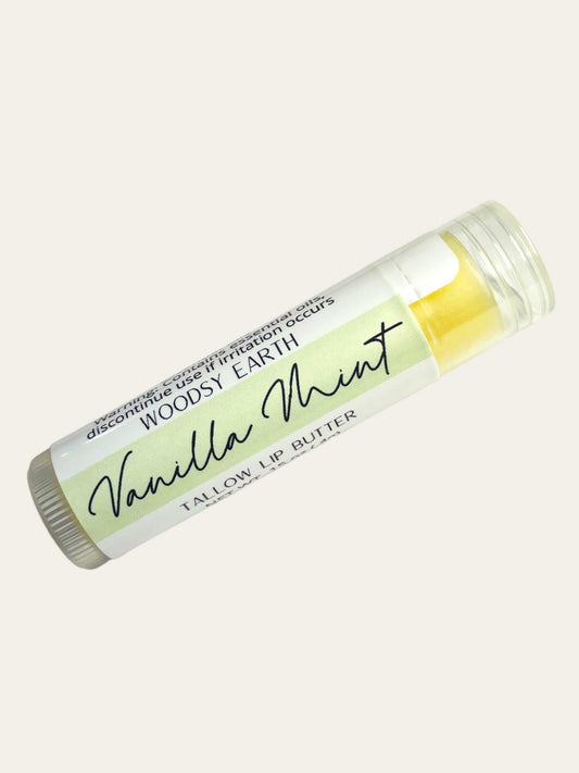 Woodsy Earth Vanilla Mint Tallow Lip Balm in a clear tube with label, .15 oz natural moisturizing lip butter.